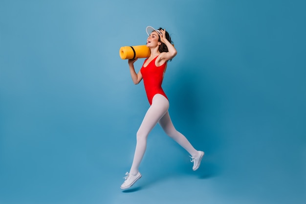 Joyful leggy brunette runs on blue wall