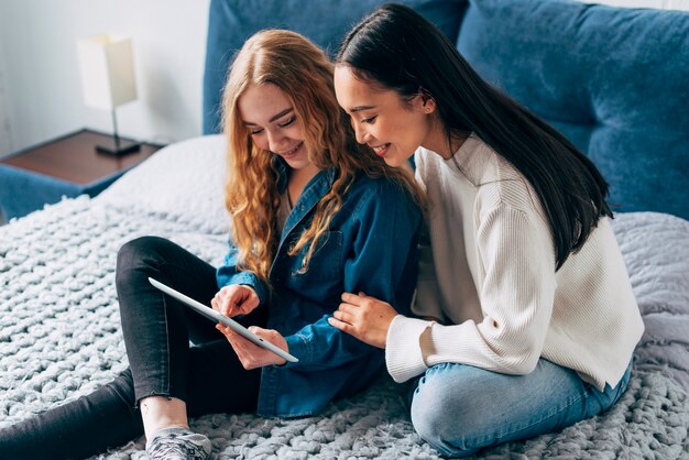 Joyful lesbian sweethearts looking at tablet