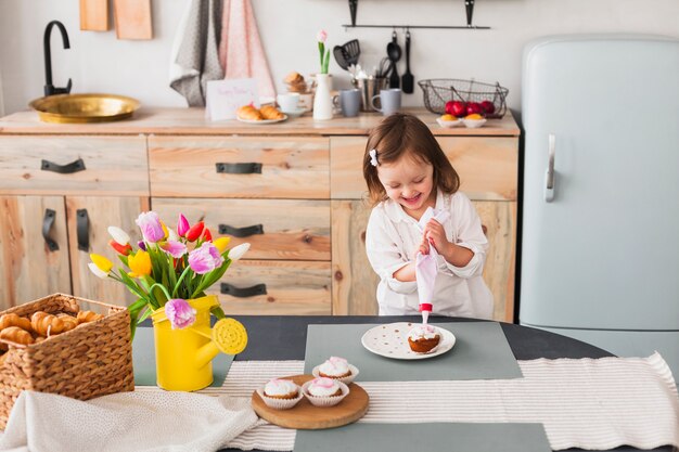 Joyful little girl making cupcake