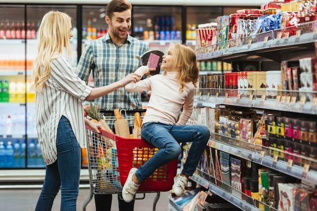 Joyful little girl sitting on a shopping cart