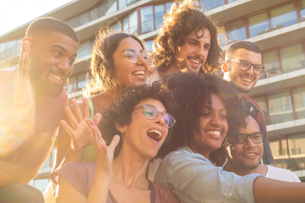 Joyful multiethnic friends taking funny group selfie