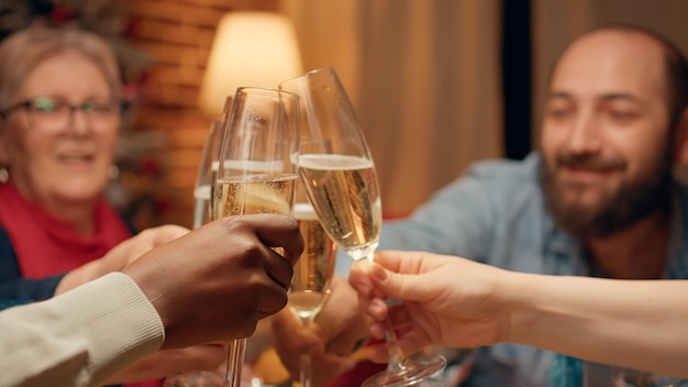 Free photo joyful people gathered at christmas dinner table to celebrate winter holiday in living room. happy smiling heartily family members celebrating traditional winter holiday at home with sparkling wine.