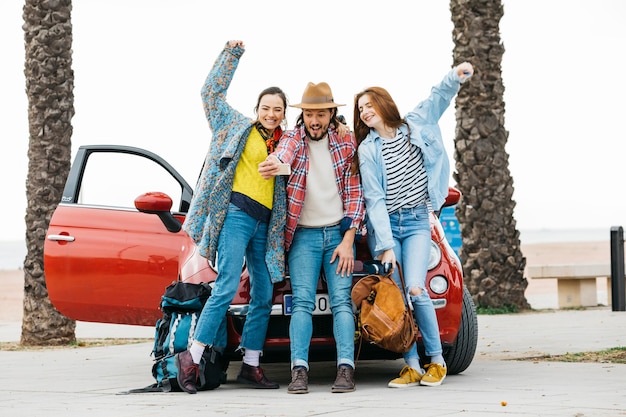 Joyful people taking selfie near red car