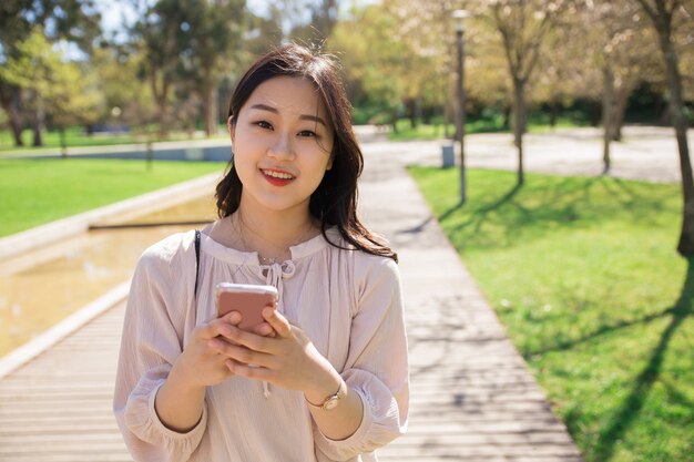 Joyful positive girl with cellphone posing outdoors