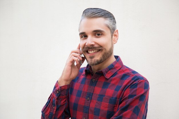 Joyful satisfied man talking on cell