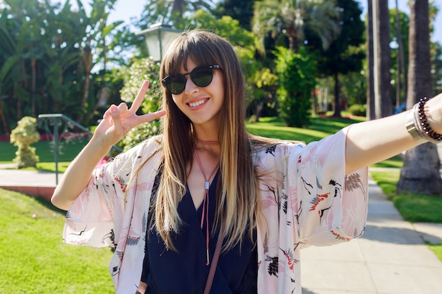 Joyful traveling   smiling long haired girl  making self portrait   on  the street in  Los Angeles.