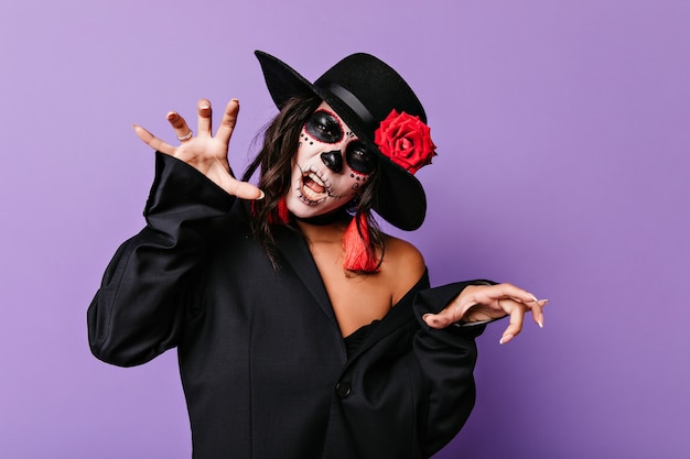 Free photo joyful woman in muertos attire having fun at party. amazing female model with zombie face painting posing in halloween.