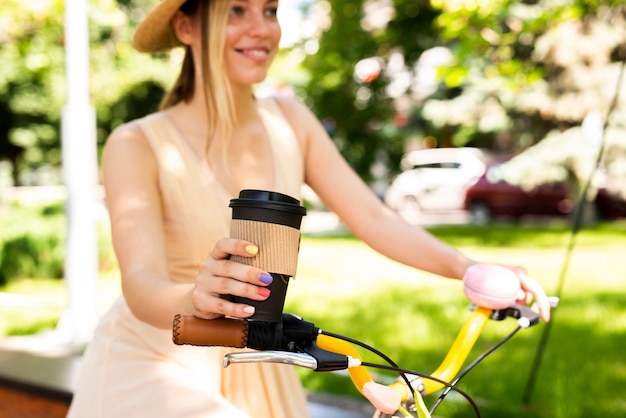 Free photo joyful woman riding bicycle with coffee