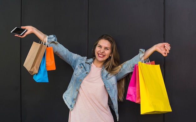 Joyful woman standing with colourful shopping bags