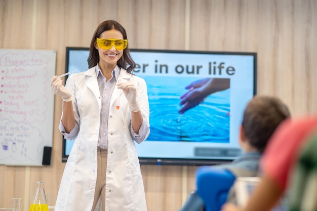 Free Photo joyful woman with test tube looking at children