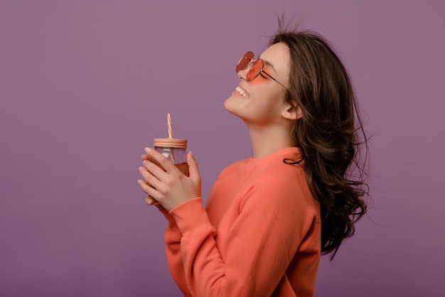 Free photo joyful young caucasian brunette girl enjoys drink with her eyes closed on purple background lifestyle female beauty concept