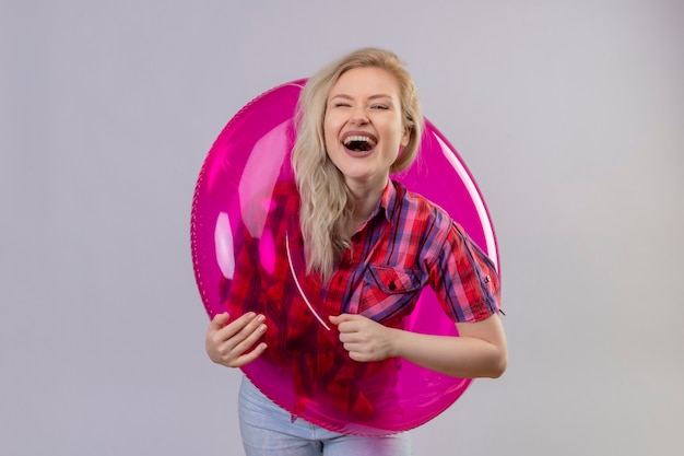 Free photo joyful young female traveler wearing red shirt in inflatable ring on isolated white wall