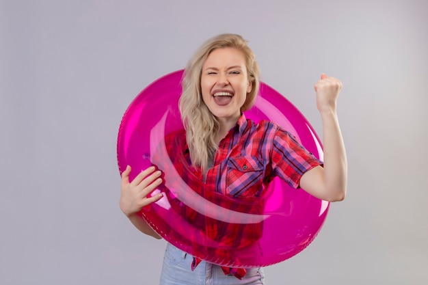 Free Photo joyful young female traveler wearing red shirt in inflatable ring raised fist on isolated white wall