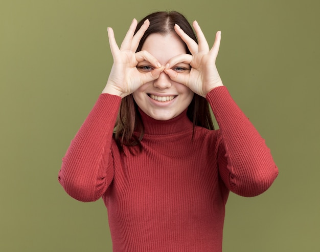 Joyful young pretty girl wearing sunglasses doing look gesture using hands as binoculars 