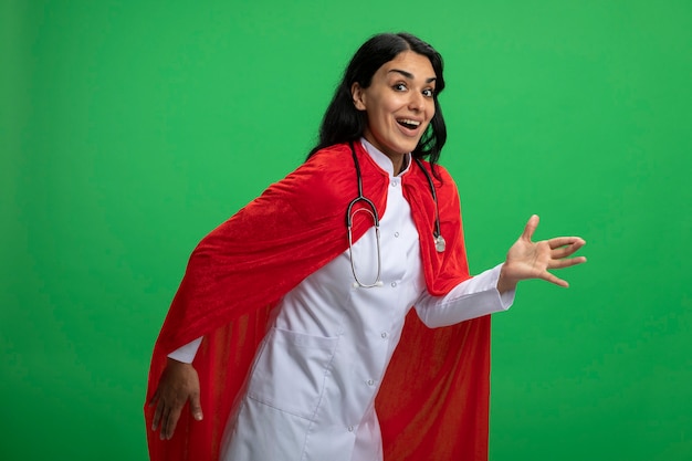 Joyful young superhero girl wearing medical robe with stethoscope showing robot style isolated on green