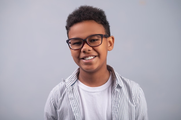 Free photo joyous cute boy in eyeglasses posing for the camera