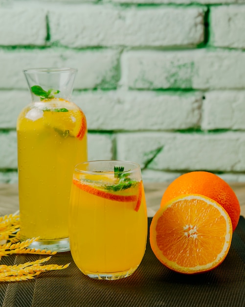 Free photo jug of citrus lemonade glass orange mint sparkling water side view