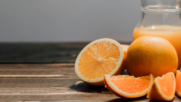 Jug of delicious orange juice surrounded by oranges with copy space