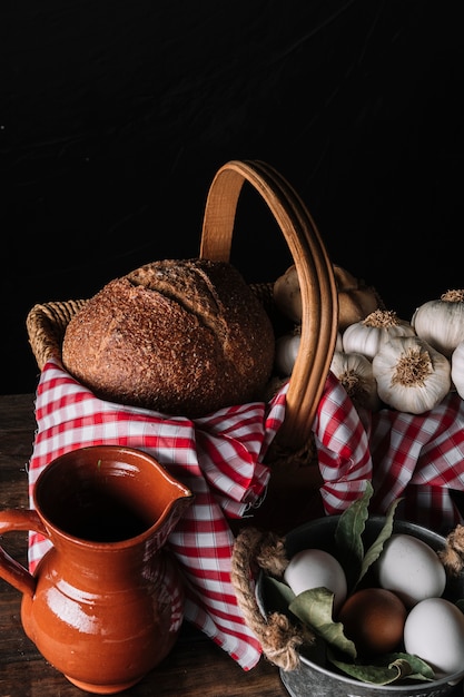 Jug and eggs near basket with food