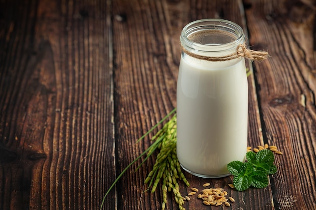 Jug of rice milk with rice plant and rice seed put on wooden floor