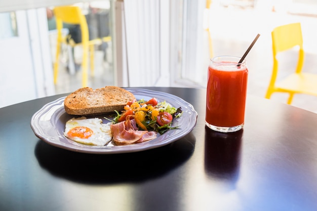 Juice; fresh breakfast on gray plate over the black table