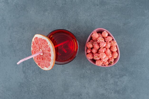 Juice glass and a bowl of popcorn candy on marble background. High quality photo