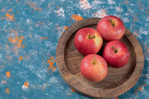 Juicy apples on round wooden plate.