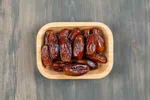 Free photo juicy dates in a wooden plate on a wooden table . high quality photo