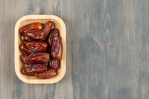 Juicy dates in a wooden plate on a wooden table . High quality photo