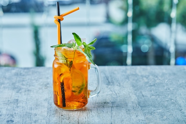 Juicy lemonade with straw and mint on the marble surface