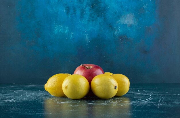 Juicy lemons and red apple on marble table. 