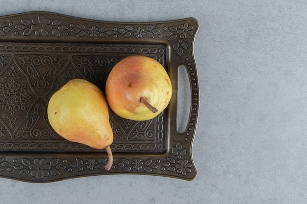 Free photo juicy pears on an ornate tray on marble