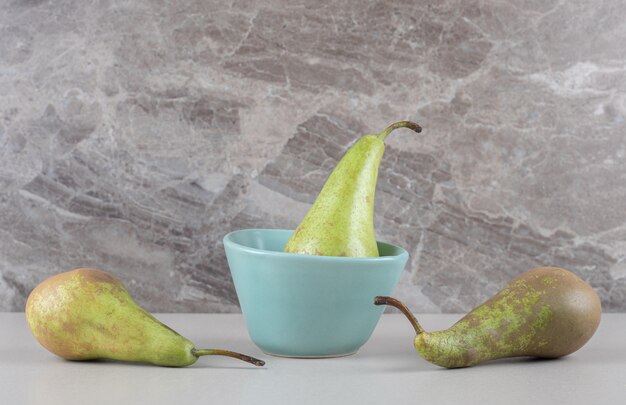 Juicy pears in and next to a tiny bowl on marble 