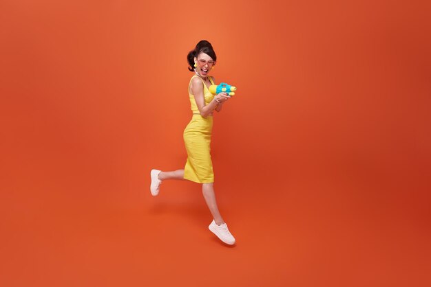 Jumping tourist woman traveling with water gun during Songkran festival