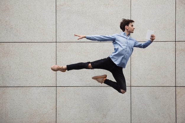 Free photo jumping young buinessman in front of buildings, on the run in jump high