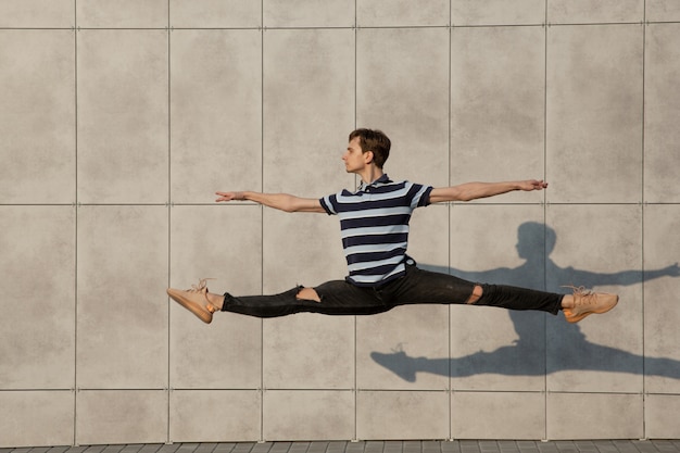 Free Photo jumping young buinessman in front of buildings, on the run in jump high