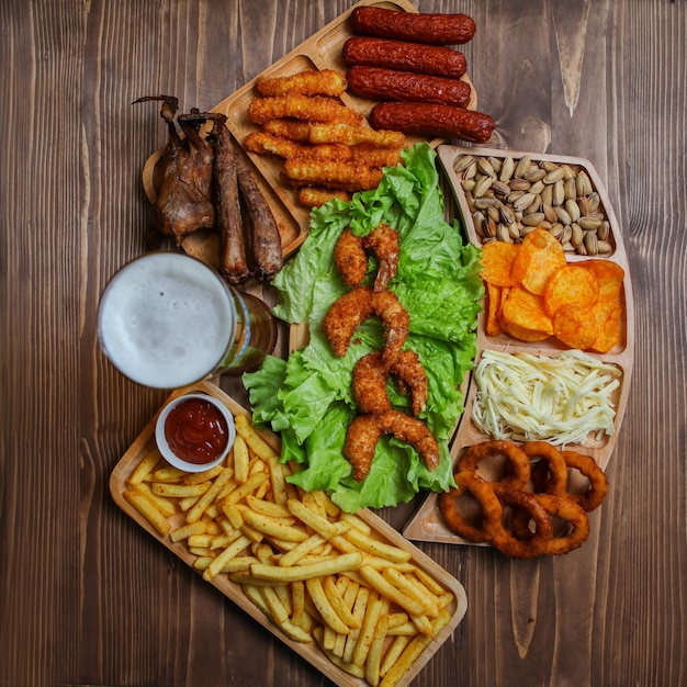 Free Photo junk food products in wooden plates with beer, cheese, barbecue, pistachio top view