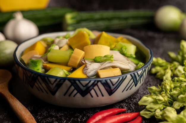 Kaeng Liang in a bowl with spices on a black cement floor.