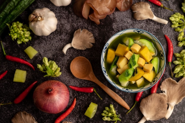 Free photo kaeng liang in a bowl with spices on a black cement floor.