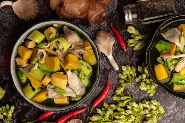 Free photo kaeng liang in a bowl with spices on a black cement floor.