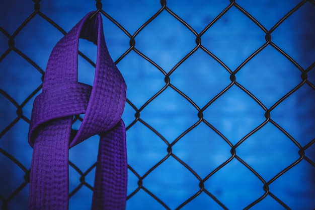 Free Photo karate purple belt hanging on wire mesh fence