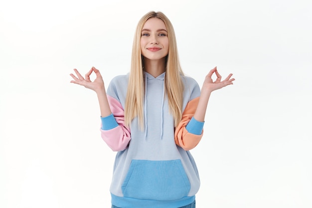 Free photo keep calm and do shopping online. peaceful happy and relieved blonde attractive girl hold hands in zen gesture, smiling pleased, feel patience and peace