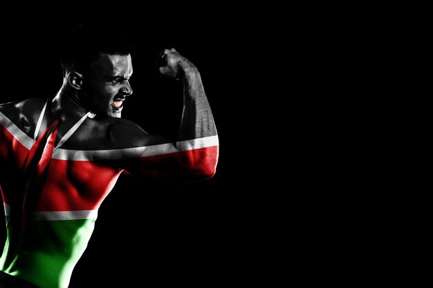 Kenya flag on handsome young muscular man black background