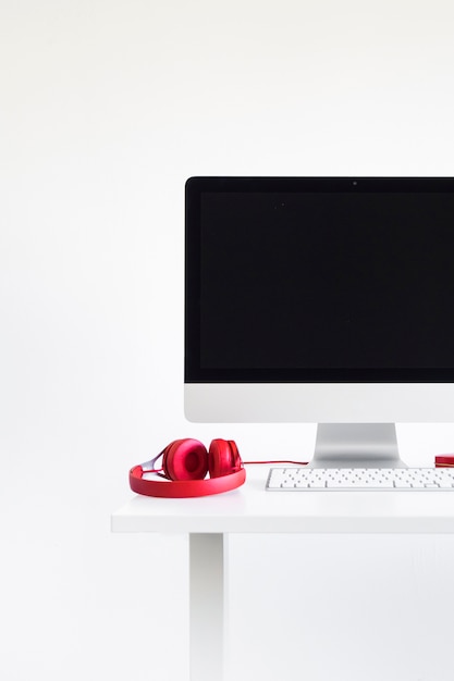 Free photo keyboard near monitor and red headphones on table