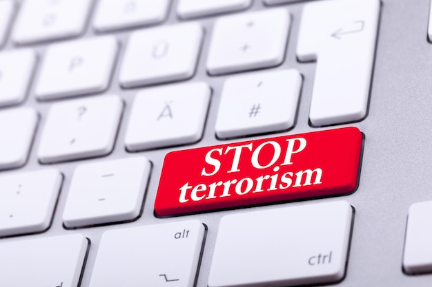 Free photo keyboard with red button and stop terrorism word on it. stop the war and abuse