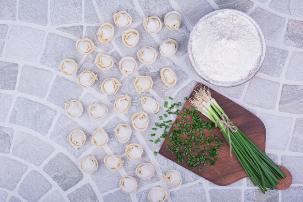 Khinkali stuffings in flour served with a bunch of green onion.