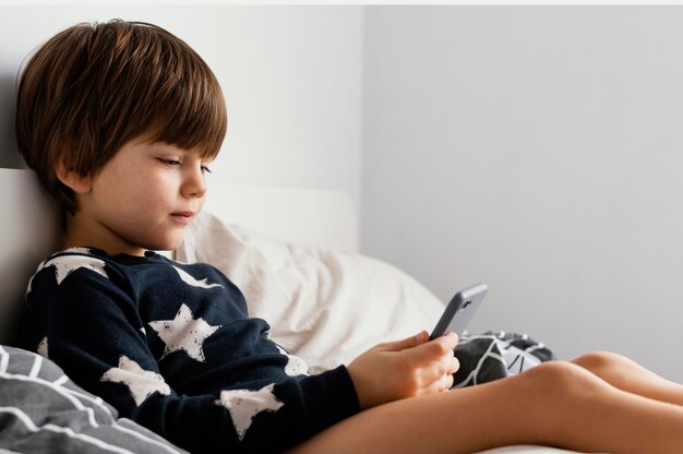 Kid in bed holding smartphone