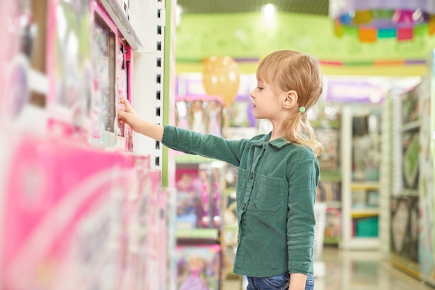 Kid choosing toys for purchase in big store.