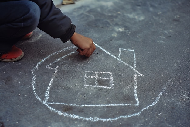 Kid drawing house with chalk on the floor