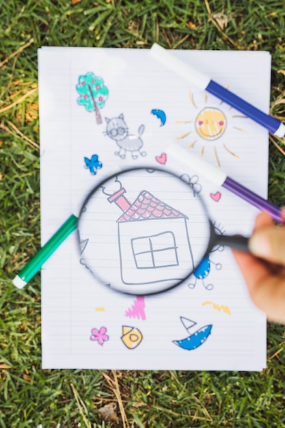 Free Photo kid drawing through magnifier above green grass